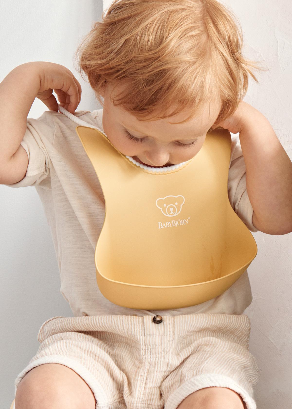 Bib in yellow with a big spill pocket - BabyBjörn